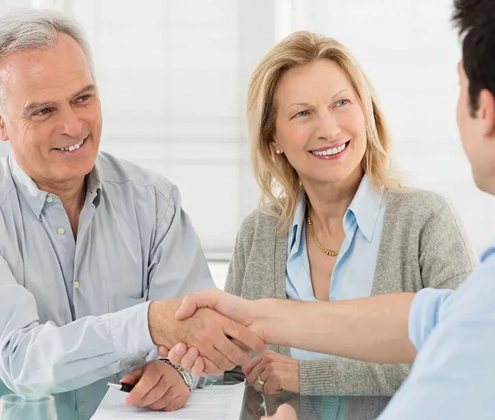 A man and woman shaking hands over a table.